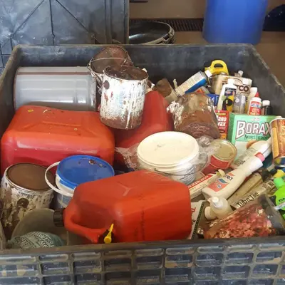 A bin filled with various containers of household hazrdous waste.