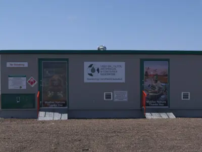 Recycling center building with signage, two doors, and a clear blue sky in the background.