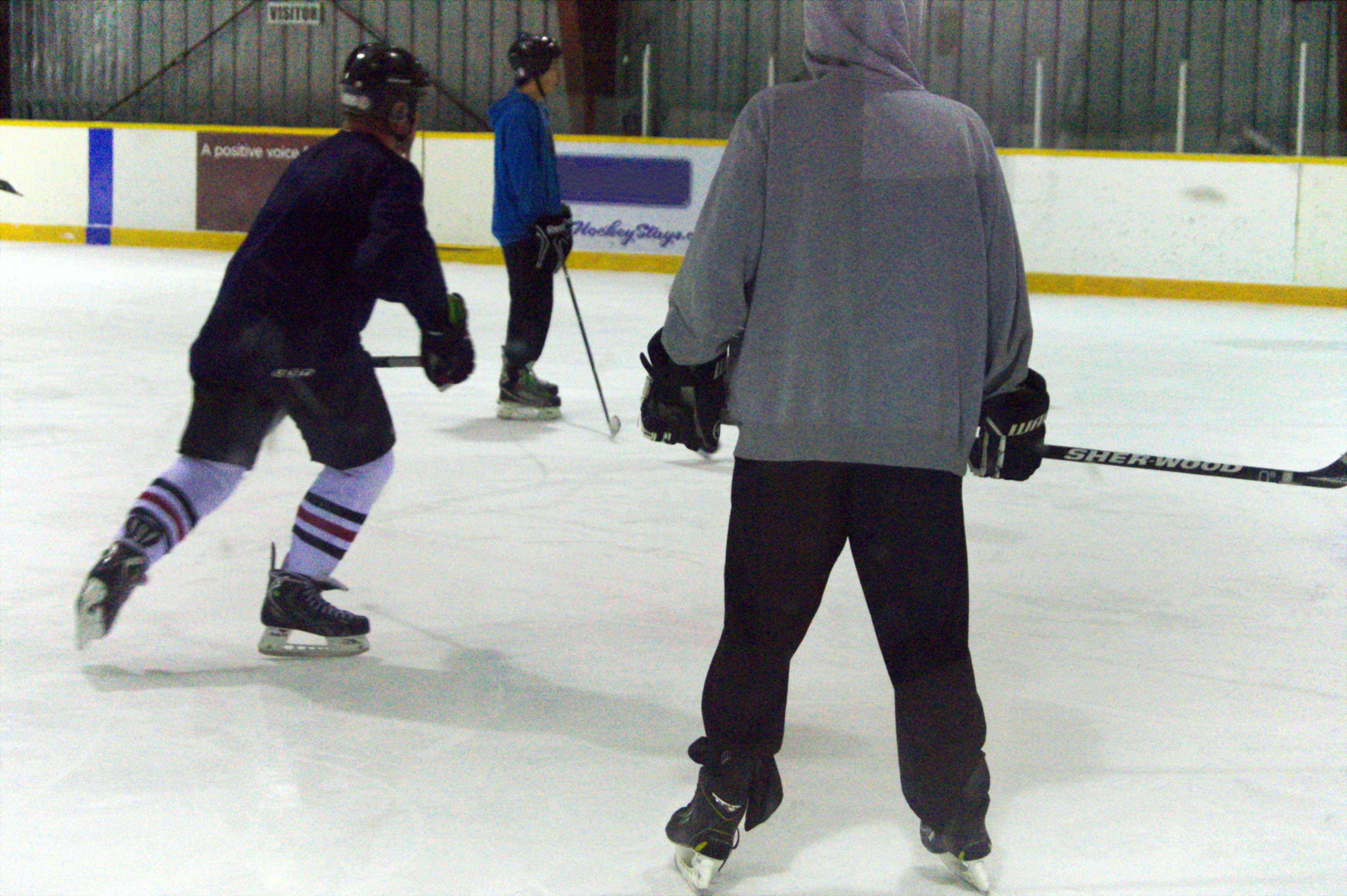 Three skaters playing shinny hockey on the ice at Ron Ross Arena.
