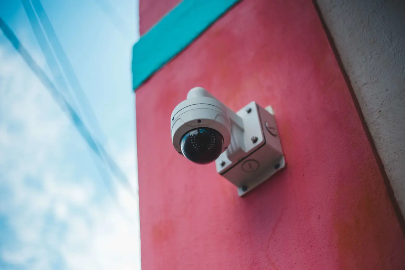 A security camera on a brightly coloured exterior wall.