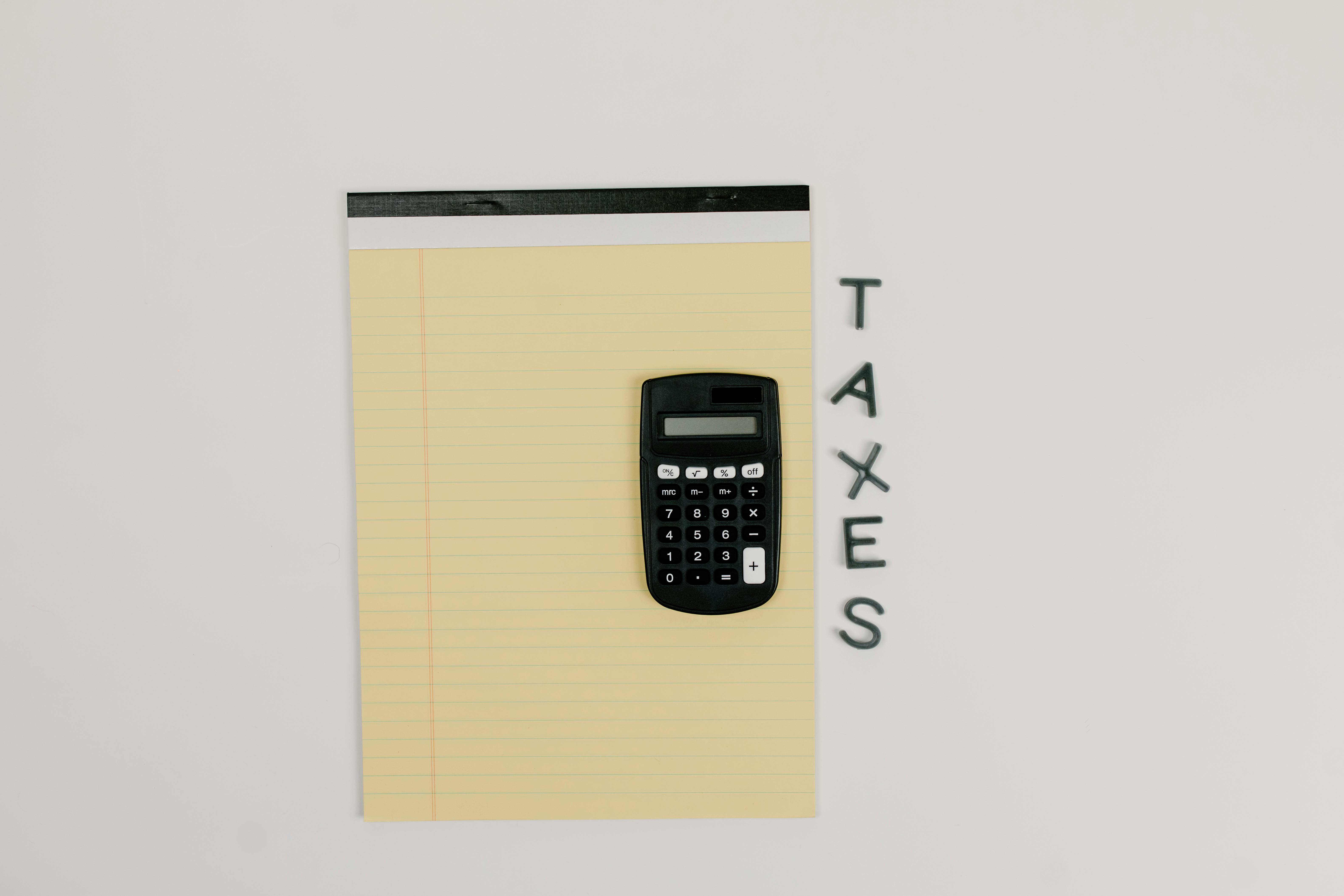 Calculator on a notepad with the word "TAXES" written beside it.