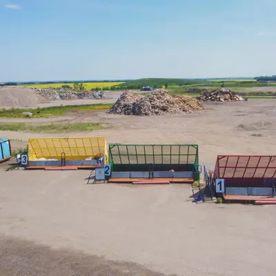 Aerial view of a waste management facility featuring colored bins and material piles in the background.